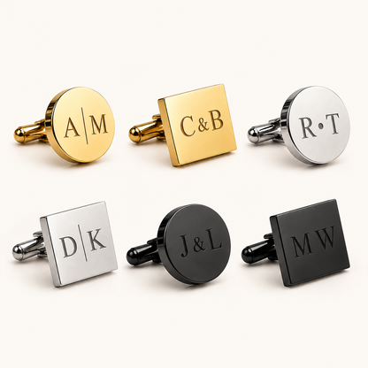 Six personalized cufflinks arranged in two rows on a light cream background. The top row features three round gold-tone cufflinks with engraved initials: 'A|M', 'C&B', and 'R|T'.