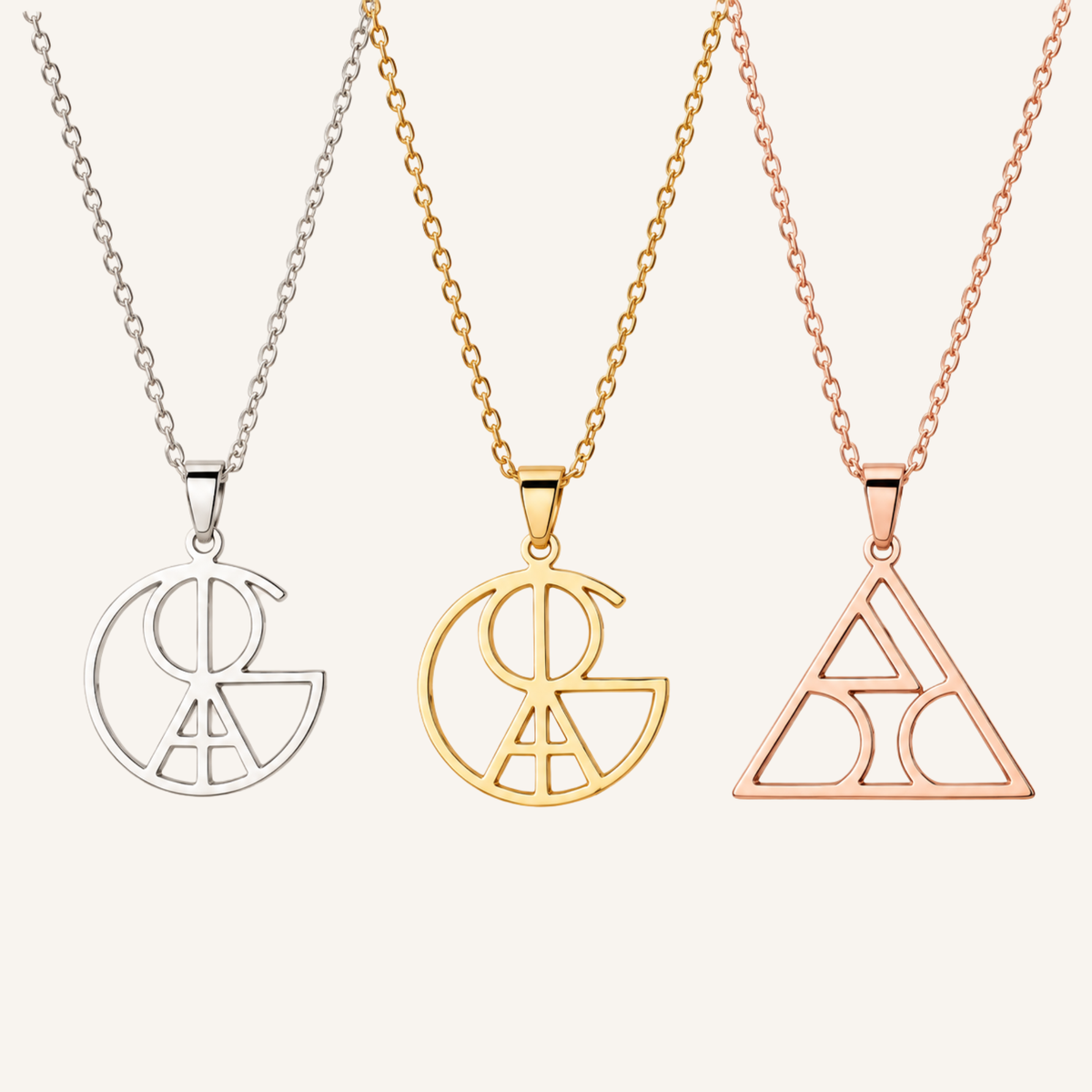 Three necklace pendants on chains against a light warm background: a silver pendant on a silver chain, a gold pendant on a gold chain, and a rose gold pendant on a rose gold chain. Each pendant features an open geometric monogram-style design.